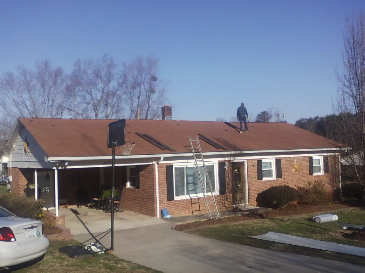 Roofer stripping a shingle roof on a brick ranch before metal panels in Decatur