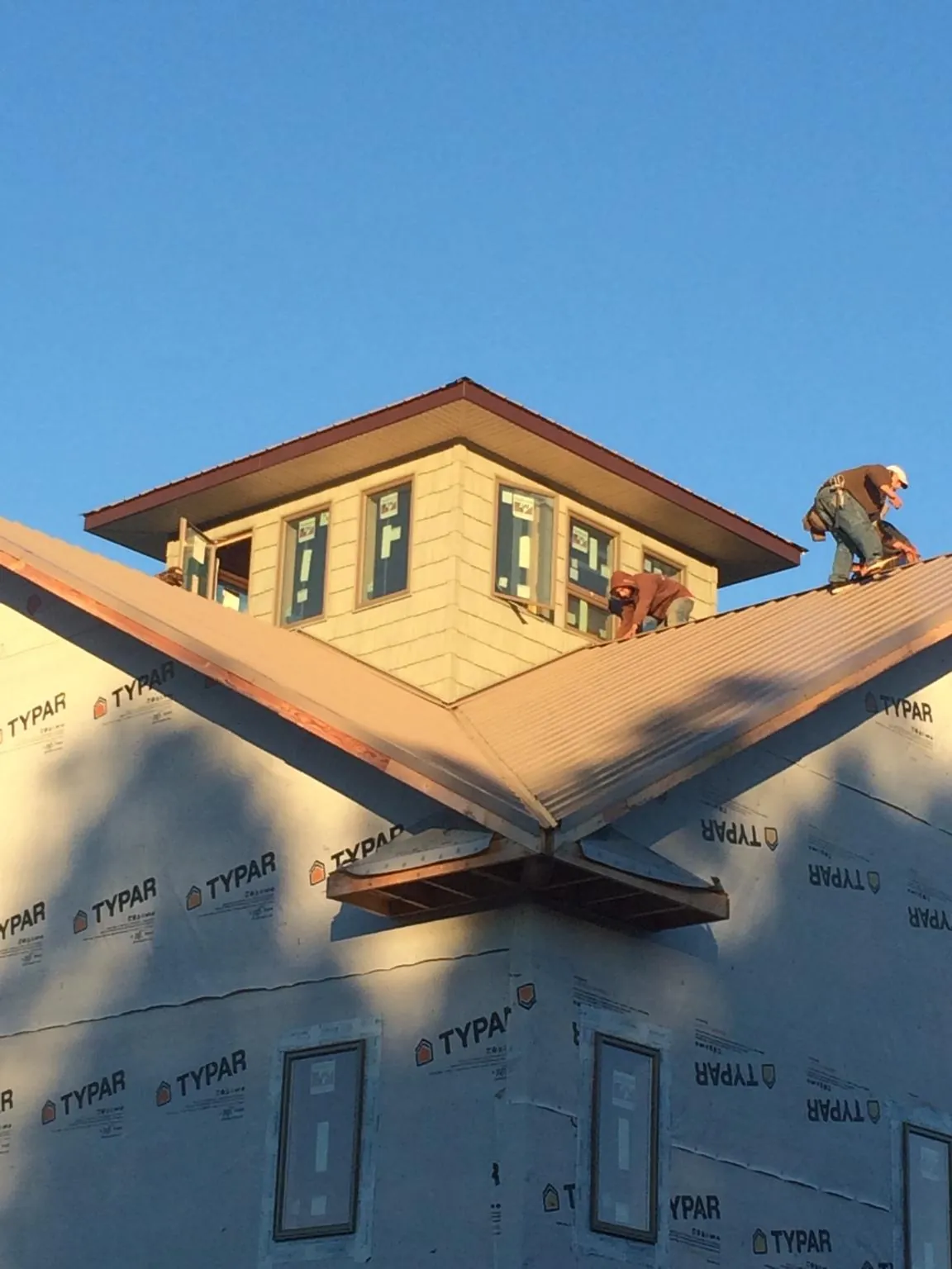 Roofers working around a rooftop cupola on a new metal roof at sunset — Roof Waterproofing in Decatur by Roofing Brothers
